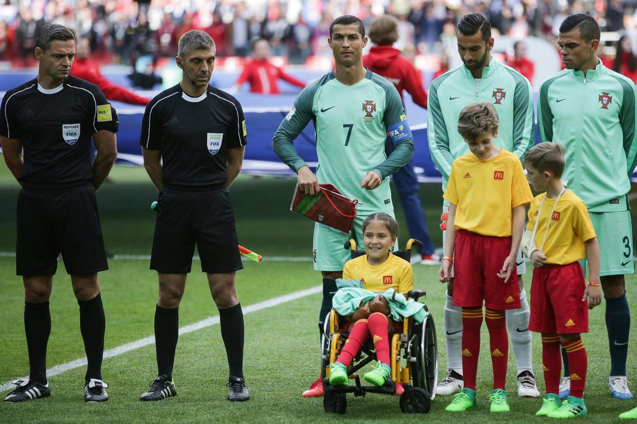 Cristiano Ronaldo regaló su sudadera a la pequeña en silla de ruedas que lo acompañó al terreno de juego. (EFE)