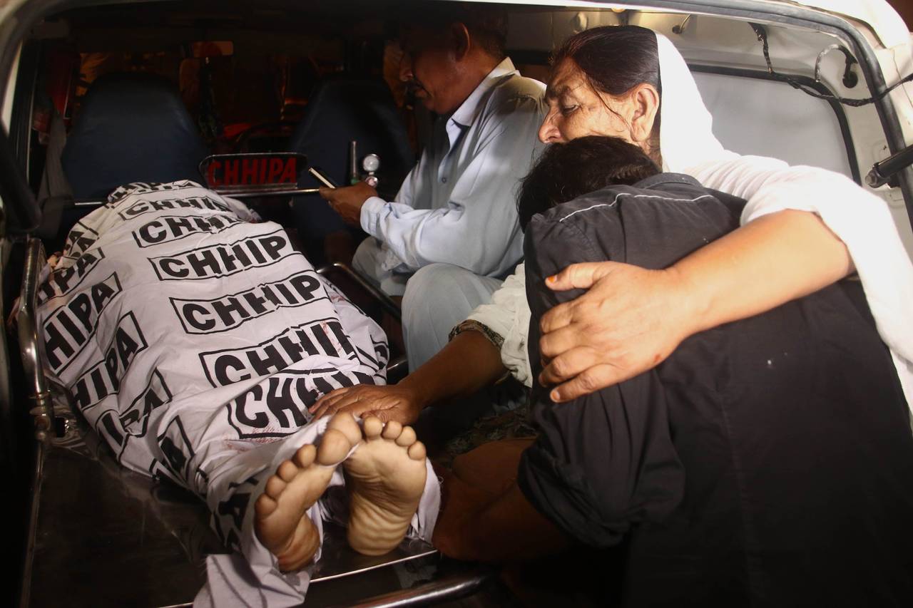 Lamentos. Familiares de una de las víctimas de los ataques en Pakistán, acompañan sus restos en una ambulancia.