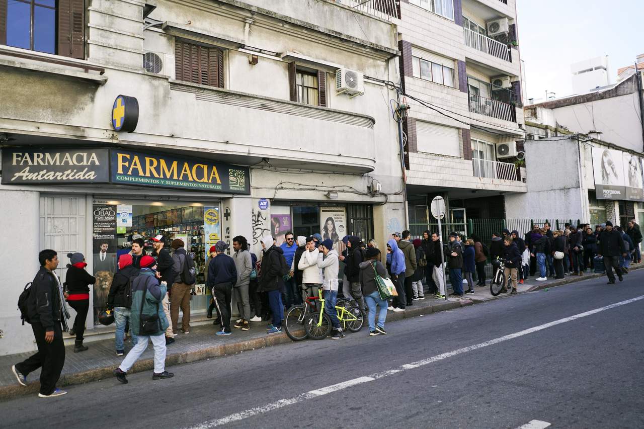 Uruguayos hacen largas colas para comprar marihuana en las farmacias. (AP) 