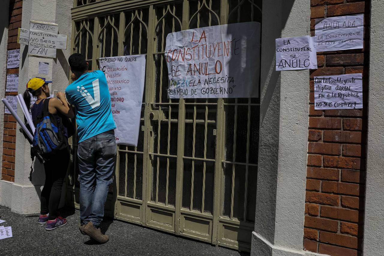 Protesta. Manifestantes pegan carteles en rechazo a la Asamblea Constituyente en un colegio electoral de Caracas.