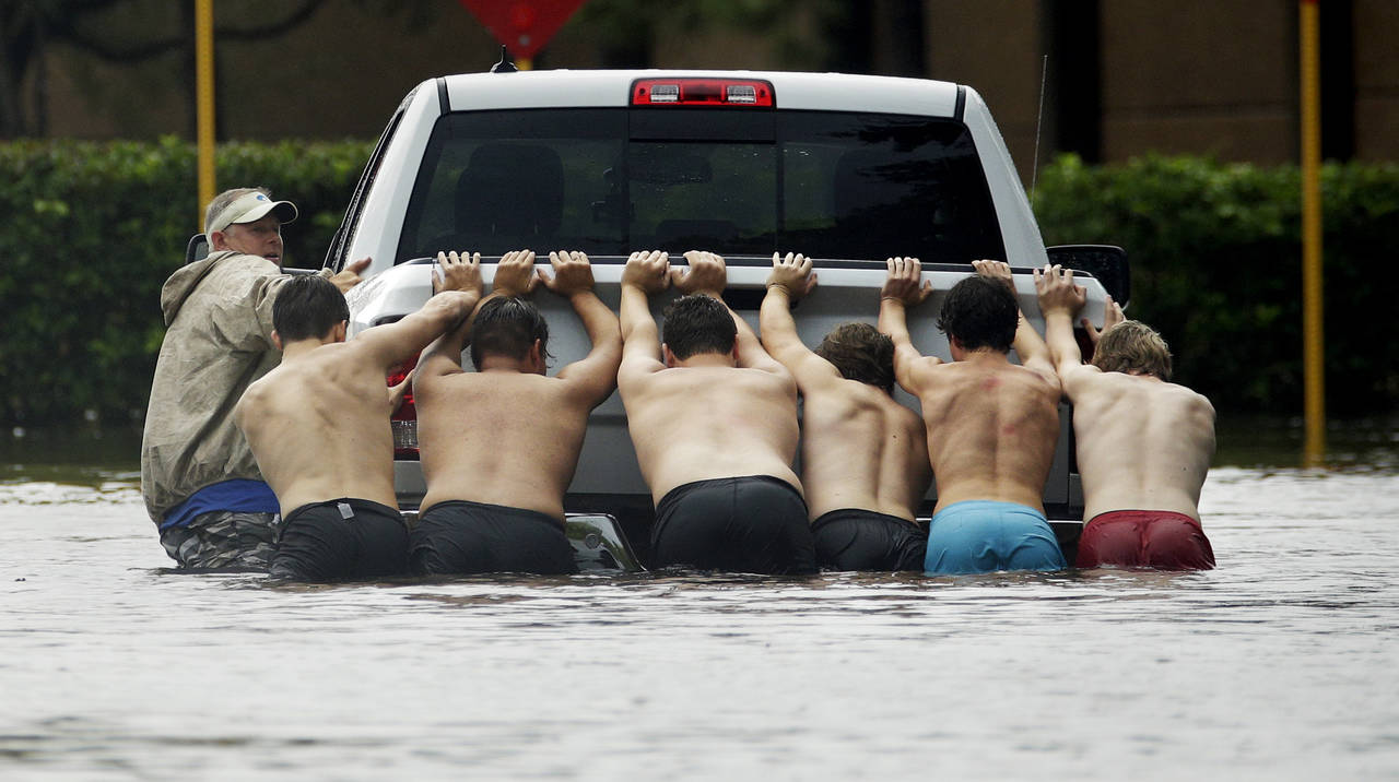 Solidarios. Varios jóvenes ayudaron a empujar los vehículos que se quedaron varados en las calles inundadas. (AP)