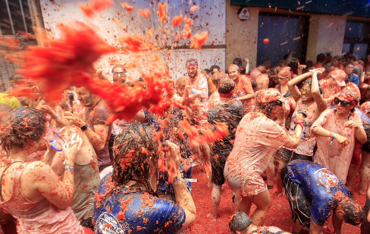 Los asistentes se arrojan toneladas de tomates maduros hasta terminar bañados en pulpa roja. (AP)

