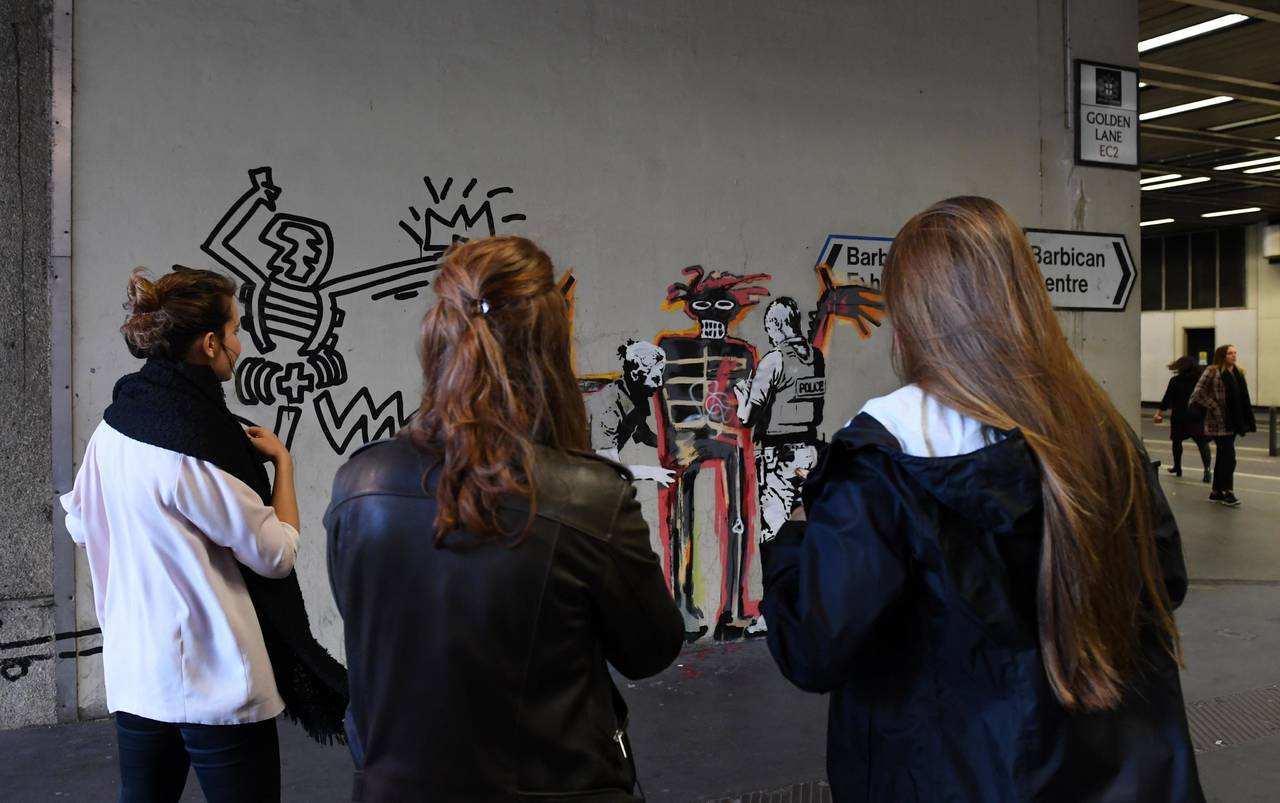 Impacto. Varios ciudadanos toman fotografías de una obra del artista Banksy, en Londres.