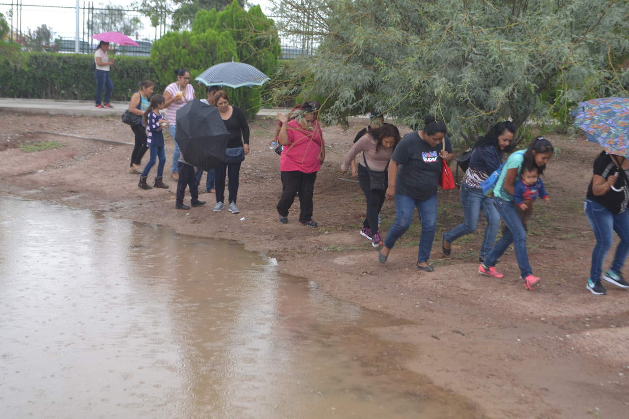 El agua comenzó a correr ocasionando que muchos de los beneficiarios se pusieran de pie, otros tantos, cargaron con sus paraguas y rompevientos para protegerse del aguacero. (ANGÉLICA SANDOVAL)