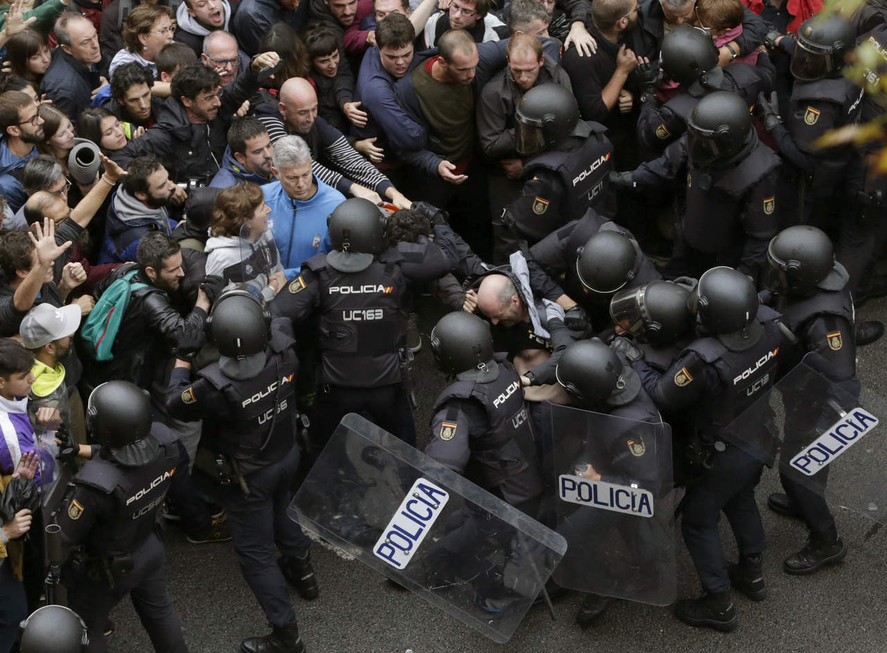 Agentes antidisturbios de la Policía Nacional forman un cordón de seguridad frente al colegio Ramón Llull de Barcelona. (EFE)