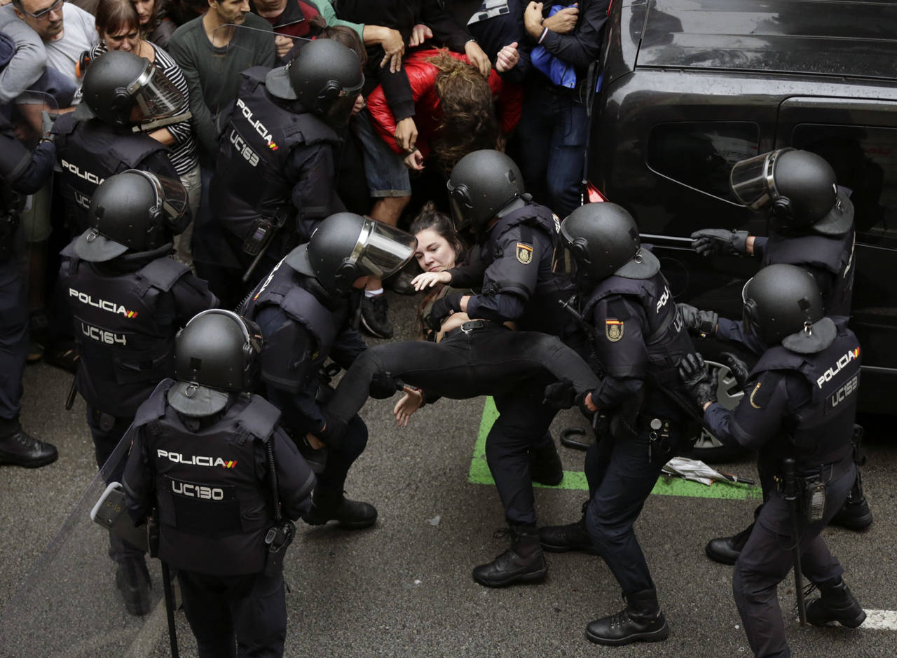 Acatar la orden. Miles de policías nacionales y guardias civiles trasladados a Cataluña se ocuparon, en algunos casos con extrema violencia, de impedir el referéndum en Cataluña. (AP y EFE)  