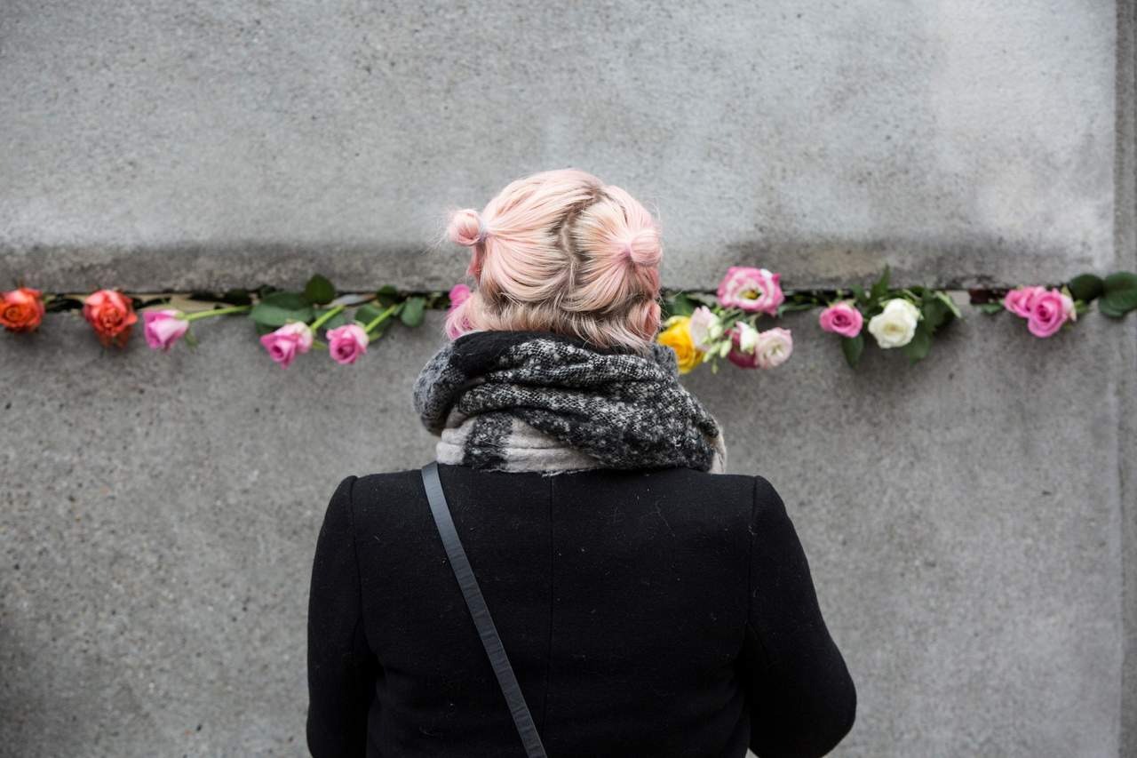 Ciudadanos depositan rosas en los restos del muro de Berlín. (EFE)