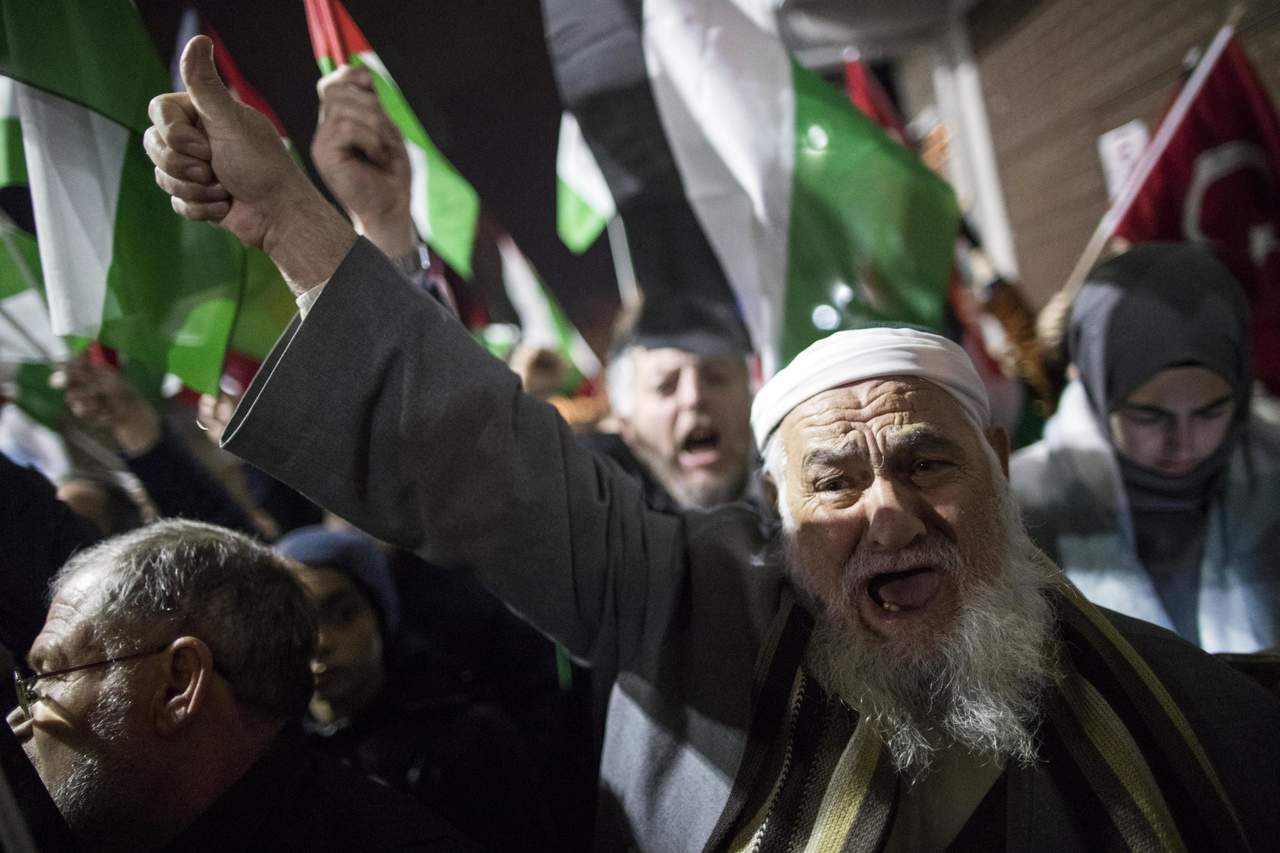  Manifestantes gritan consignas contra el presidente de los Estados Unidos, Donald Trump, durante una protesta donde sostienen banderas turcas y palestinas. (EFE) 