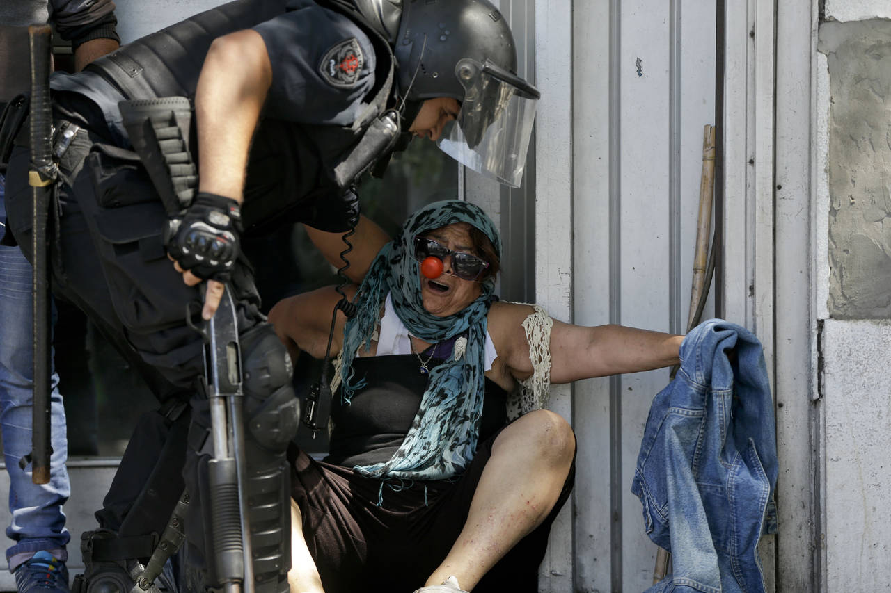 Fuerza. Un policía trata de mover a una mujer mayor, que protestaba por la reforma a pensiones. (AP)
