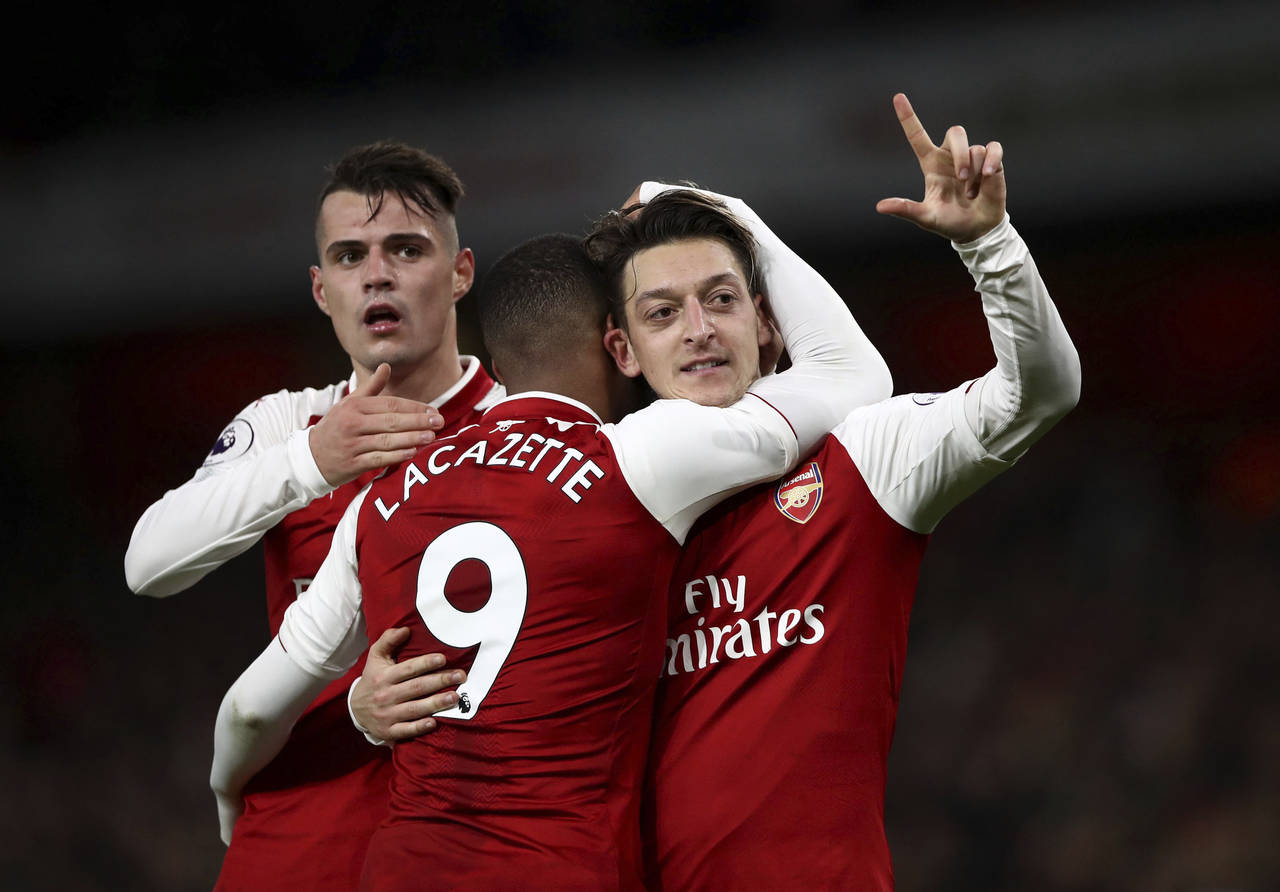 Mesut Ozil (d) celebra su gol, tercero del Arsenal, en el juego de ayer. (AP)