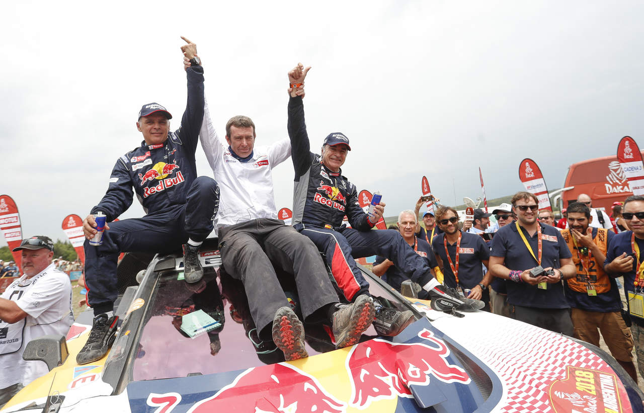 El español Carlos Sainz (d) celebra con su copiloto y compatriota Lucas Cruz (i) y Bruno Famine (c), mánager del equipo Peugeot, luego de ganar el Dakar 2018. (EFE)