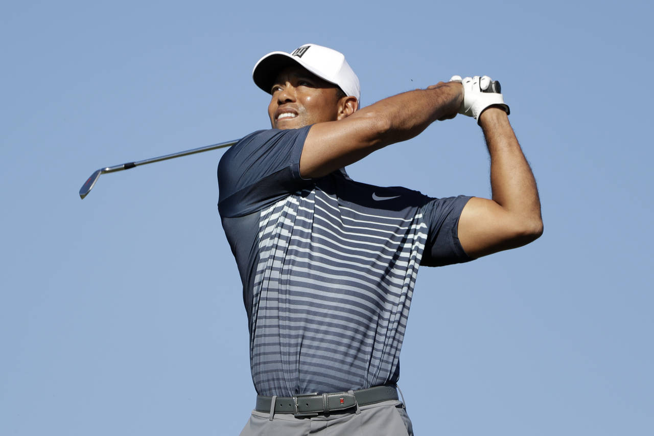 Tiger Woods suelta el palo de golf al realizar un tiro en el 12do hoyo del torneo Farmers Insurance Open.