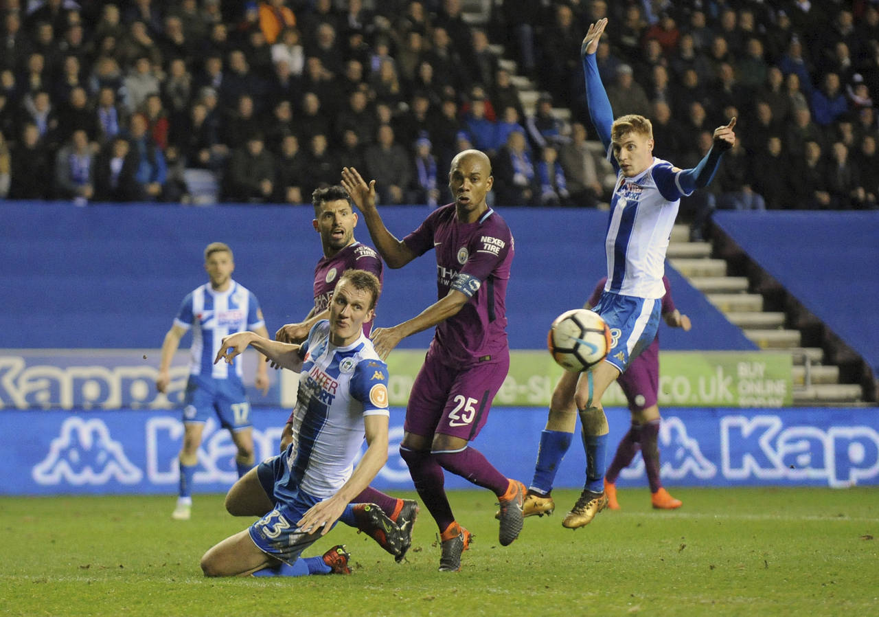 Fernandinho, del Manchester City, ve cómo se le escapa una oportunidad entre dos jugadores del Wigan. (AP)