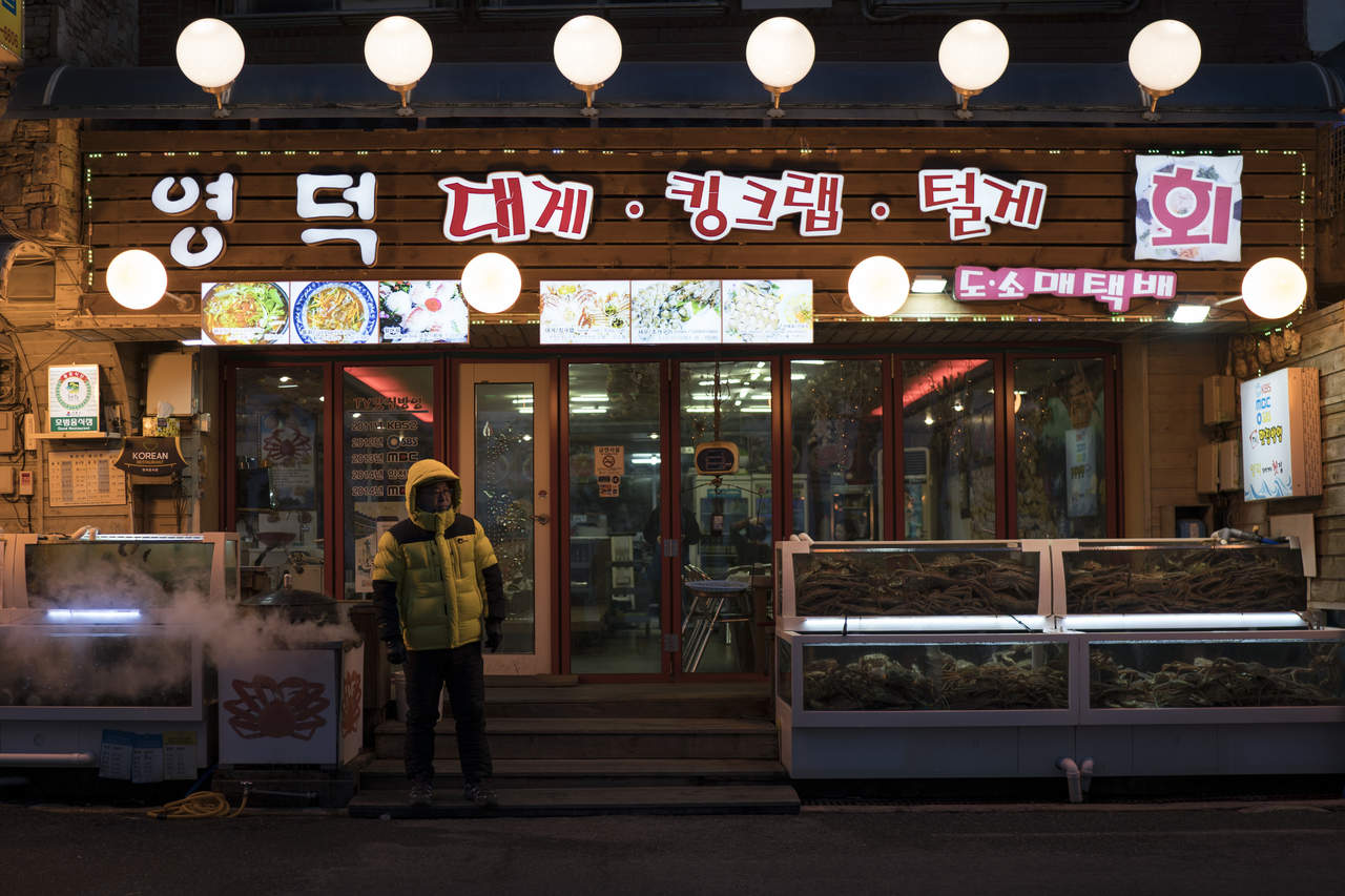 Un trabajador de un restaurante espera clientes junto a estanques de peces en Gangngeung, Corea del Sur. (AP)