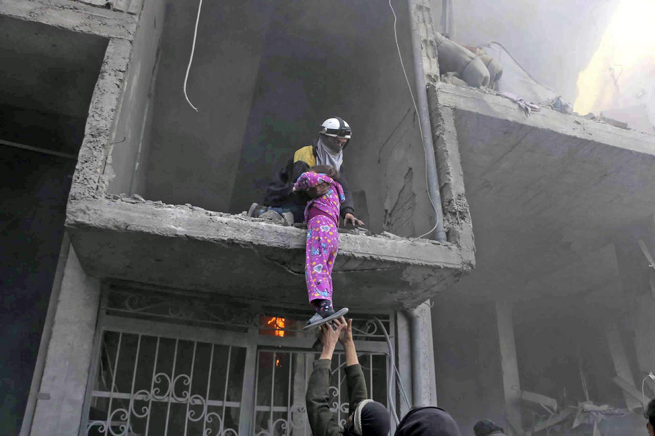 Al rescate. Cascos Blancos ayudan a bajar de una construcción bombardeada a un pequeña niña.(AP y EFE)