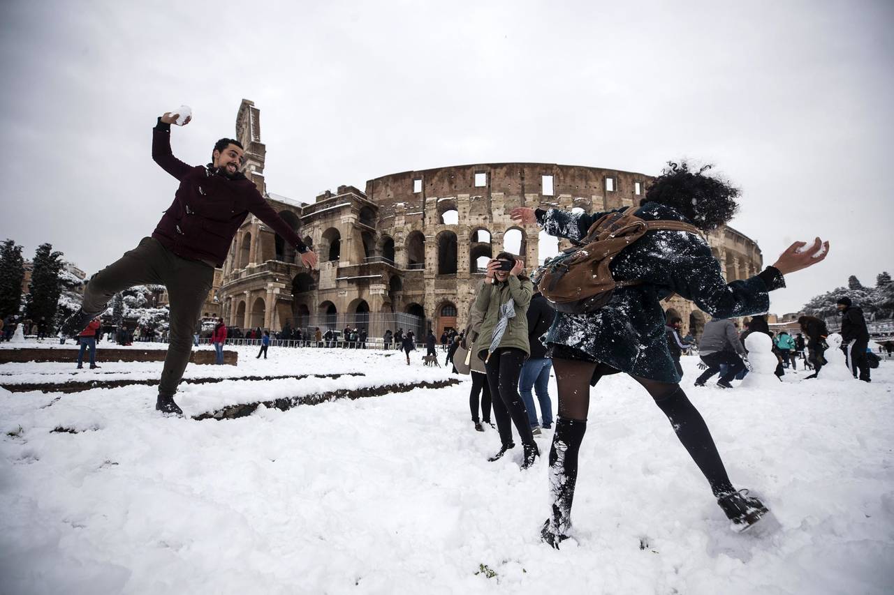 Juegan. Varias personas se lanzan nieve frente al Coliseo. (EFE)