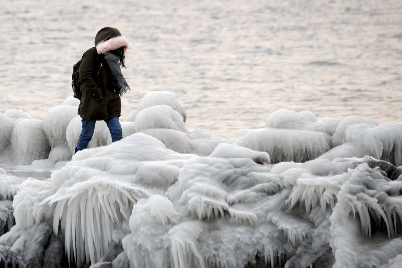Muelle. Una mujer camina en el muelle cubierto de hielo sobre la orilla del lago en Ginebra, Suiza. (AP/EFE)