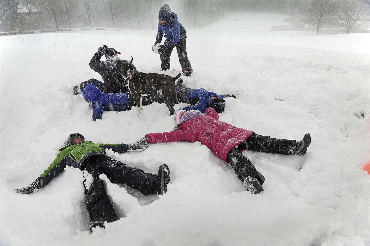 Aprovechan. La familiaHilderbrand disfrutó un momento para hacer ‘angelitos’ sobre la nieve en Richter Park de Danbury. (AP)