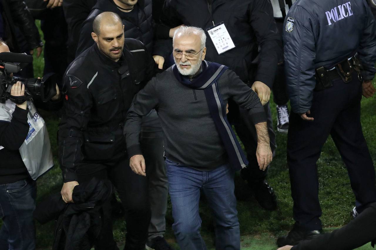 El presidente y propietario del PAOK griego, Ivan Savvidis (centro), abandona el terreno de juego escoltado por sus guardaespaldas.