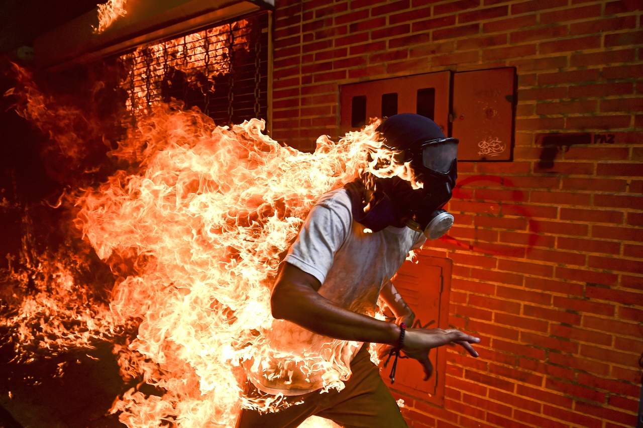 La instantánea recoge el momento en el que José Víctor Salazar, de 28 años, corre envuelto en llamas al ser alcanzado por un chorro de gasolina proveniente de una moto de la Guardia Nacional Bolivariana, que fue capturada e incendiada por los manifestantes con un cóctel molotov. (EFE)