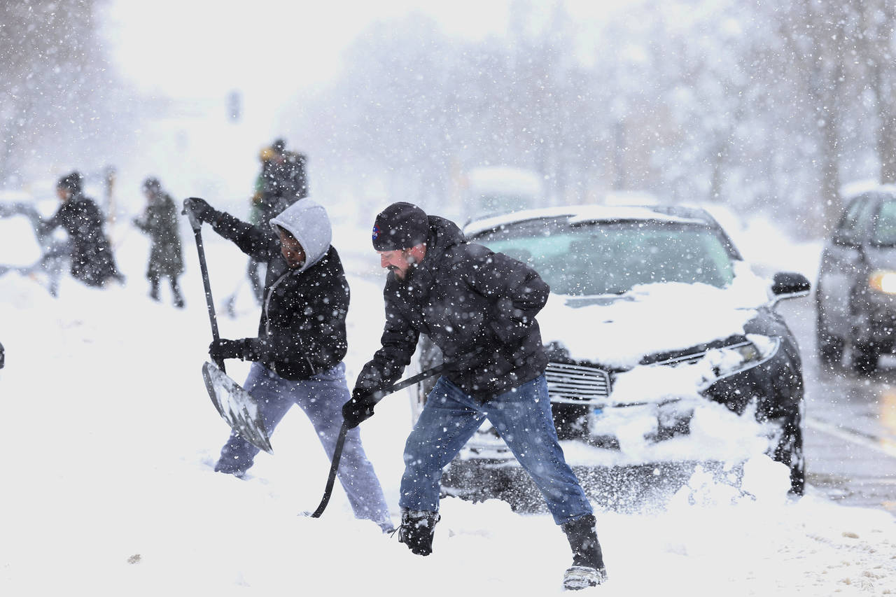 Ayuda. Vecinos se dieron la mano para tratar de quitar la nieve de las calles de Minneapolis y ayudar a la circulaciónde los autos. (AP)