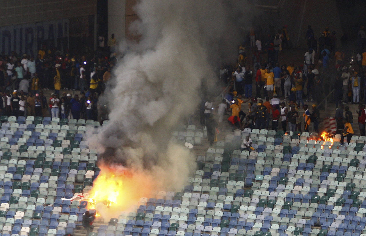Una zona de las tribunas es consumida por el fuego en el estadio Moses Mabhida de Durban, Sudáfrica, durante los disturbios de hinchas. Investigan disturbios durante partido de liga sudafricana