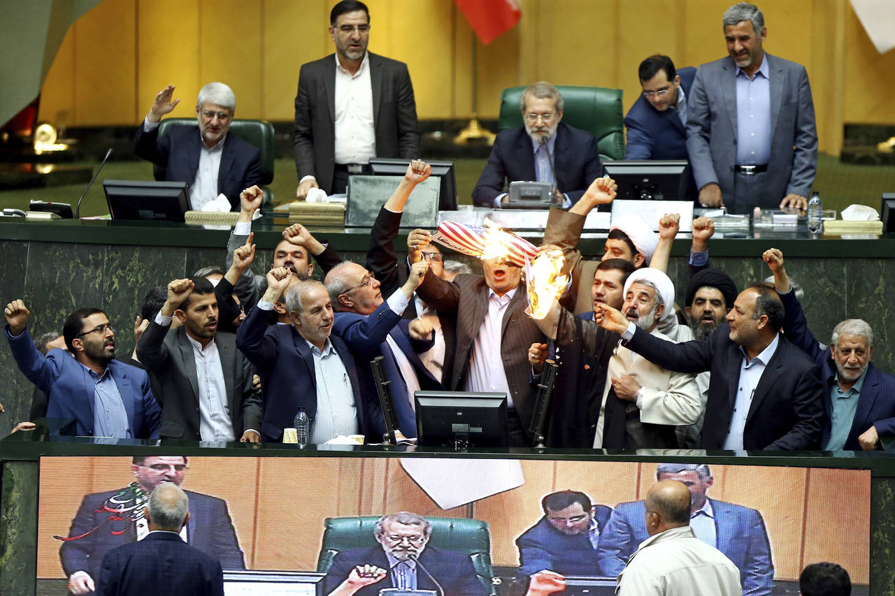 Protesta. Legisladores iraníes quemaron dos papeles que representan la bandera de EU y el acuerdo nuclear mientras corean consignas contra Estados Unidos ayer en el parlamento de Teherán. (AP)