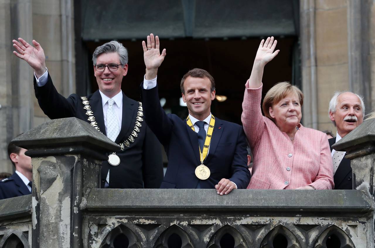 Por unidad. El presidente francés, Emmanuel Macron (Cen.), la canciller alemana, Angela Merkel (Der.), y el alcalde de Aquisgrán (Iz1.), saludan a la multitud tras la ceremonia en la que Macron recibió el Premio Carlomagno, celebrada en la Sala de la Coronación del Ayuntamiento de Aquisgrán.