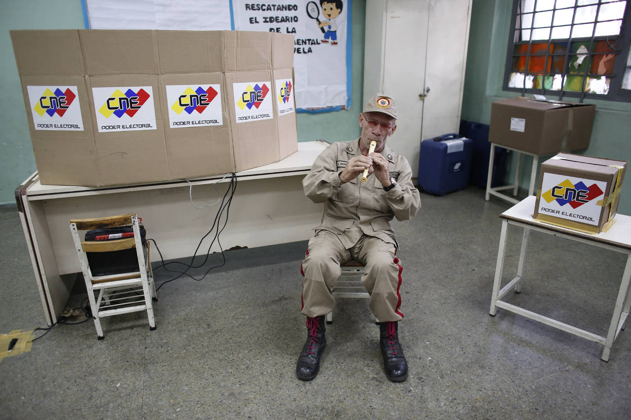 Pocos. Un miembro de la milicia bolivariana toca la flauta en una mesa de votación durante las elecciones presidenciales en Caracas. (AP)