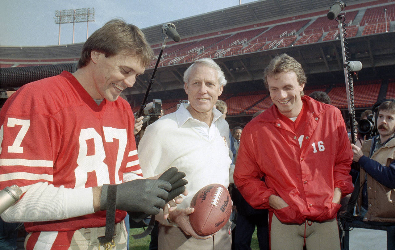 En esta fotografía de archivo del 16 de junio de 1985, el entrenador en jefe de los 49ers de San Francisco, Bill Walsh (c) sonríe con el quarterback, Joe Montana (16), y el receptor Dwight Clark (i). (Archivo)
