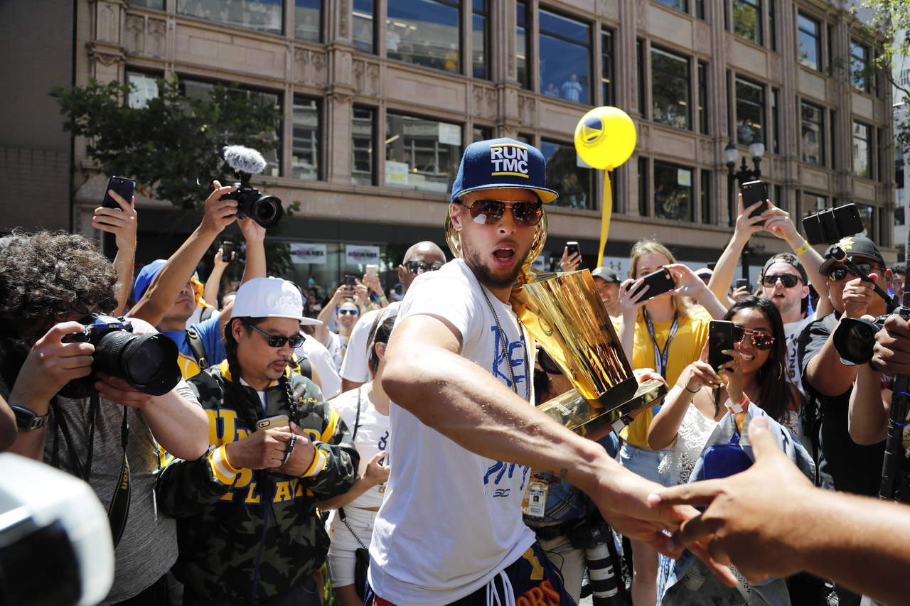 Stephen Curry bajó del autobús con el trofeo y saludó a los fans. (EFE)