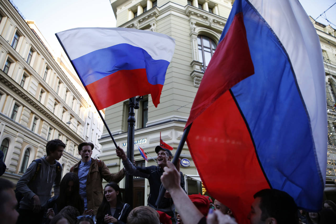 Aficionados rusos ondean banderas de su selección durante una improvisada reunión de fanáticos de los países participantes en la calle Nikolskaya la víspera de que empiece el Mundial de futbol, en Moscú. Aficionados parodian a su selección