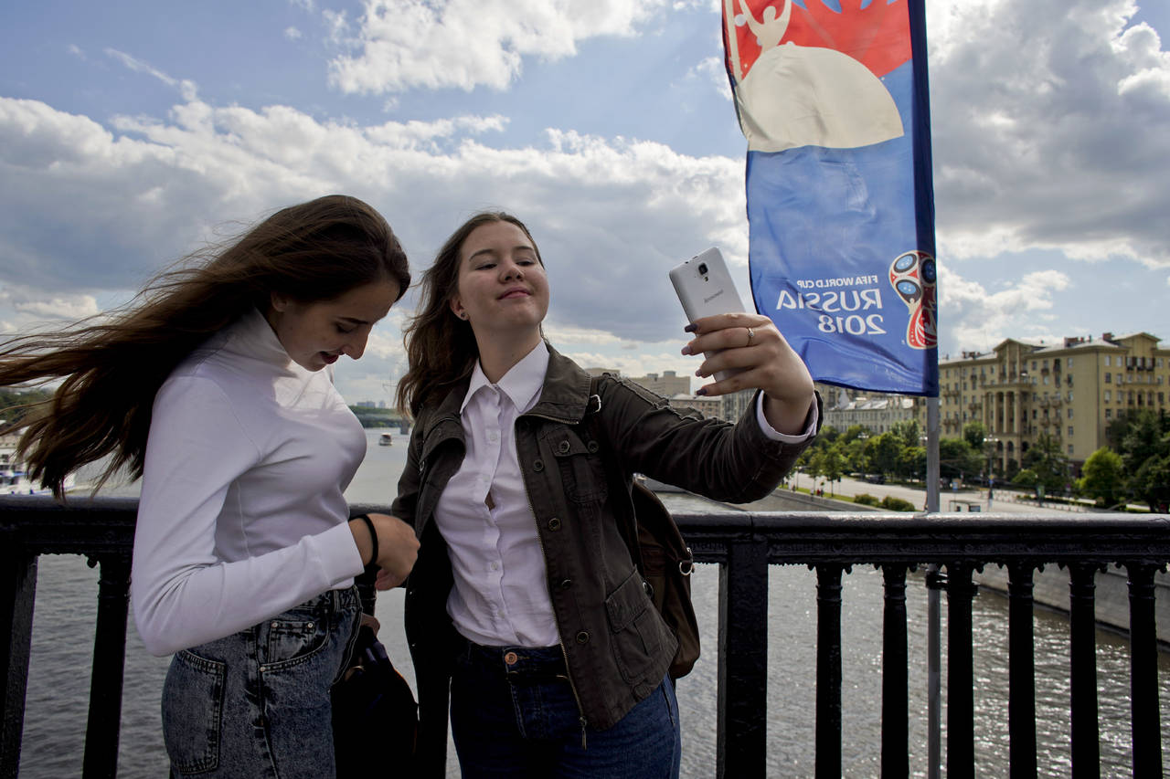 Dos mujeres se toman fotos desde el puente Krymsky de Moscú, adornado con pendones del Mundial. (AP)