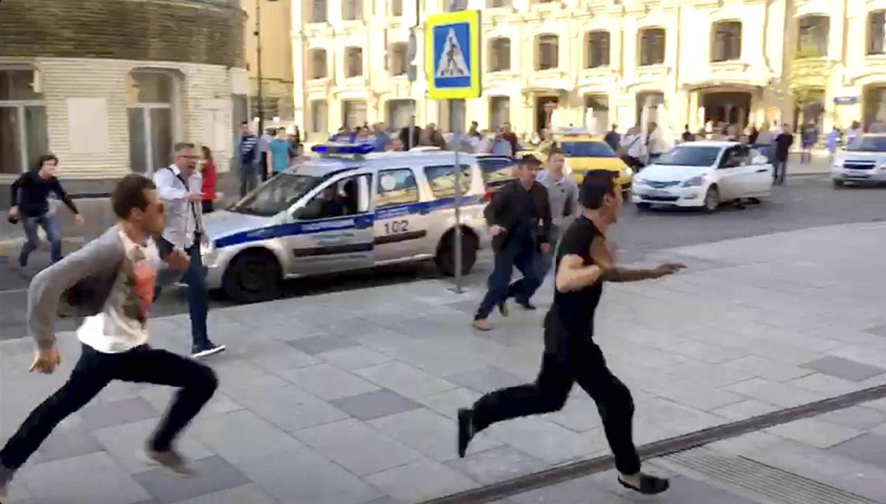 El taxista (derecha) corre del lugar donde estrelló su auto contra peatones, en una acera próxima a la Plaza Roja, en Moscú, el pasado sábado. (AP)
