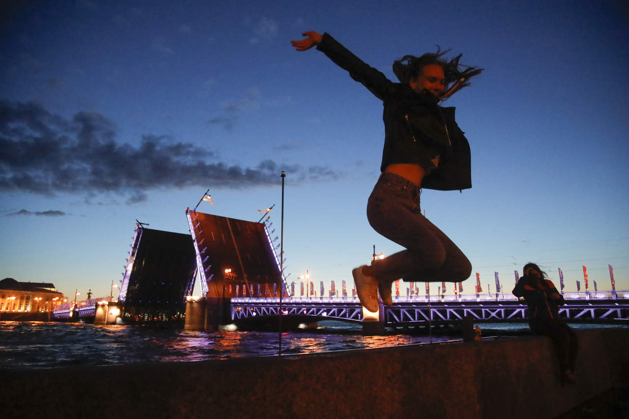 Una mujer salta cerca del puente Dvortsovy en San Petersburgo, Rusia, al amanecer. (AP)