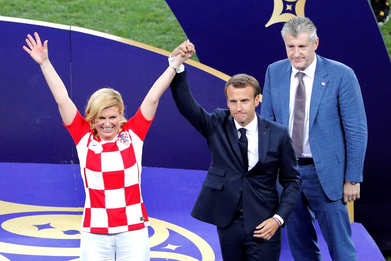El presidente francés, Emmanuele Macron (c), levanta el brazo de su homóloga croata, Kolinda Grabar-Kitarovic (i), y junto al presidente de la Federación Croata de Futbol, Davor Suker. (EFE)