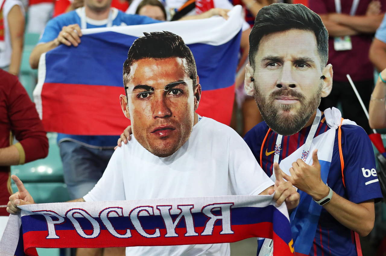 Aficionados rusos portan fotografías de Cristiano Ronaldo y Messi en sus rostros, las dos grandes decepciones.