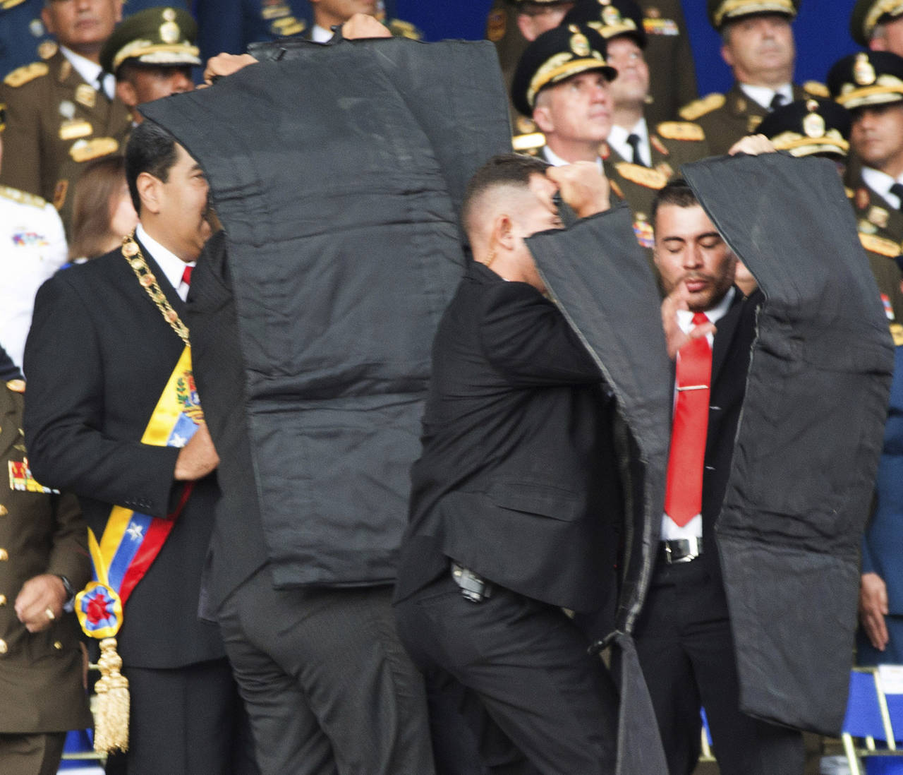 Reacción. Luego de una primera explosión, el presidente venezolano Nicolás Maduro (con la banda presidencial)  fue resguardado de inmediato por sus escoltas, luego de un supuesto atentado en su contra ayer durante un acto público con militares en Caracas. 