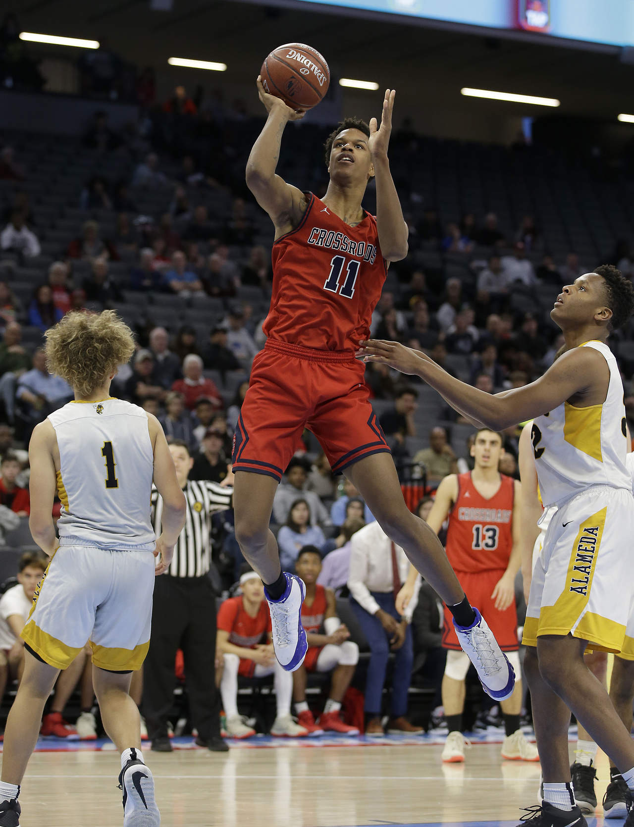 Shareef O’Neal, centro, se eleva para encestar por la escuela secundaria Crossroads en duelo con Alameda por el campeonato estatal de la Segunda División, en Sacramento, California. (AP)