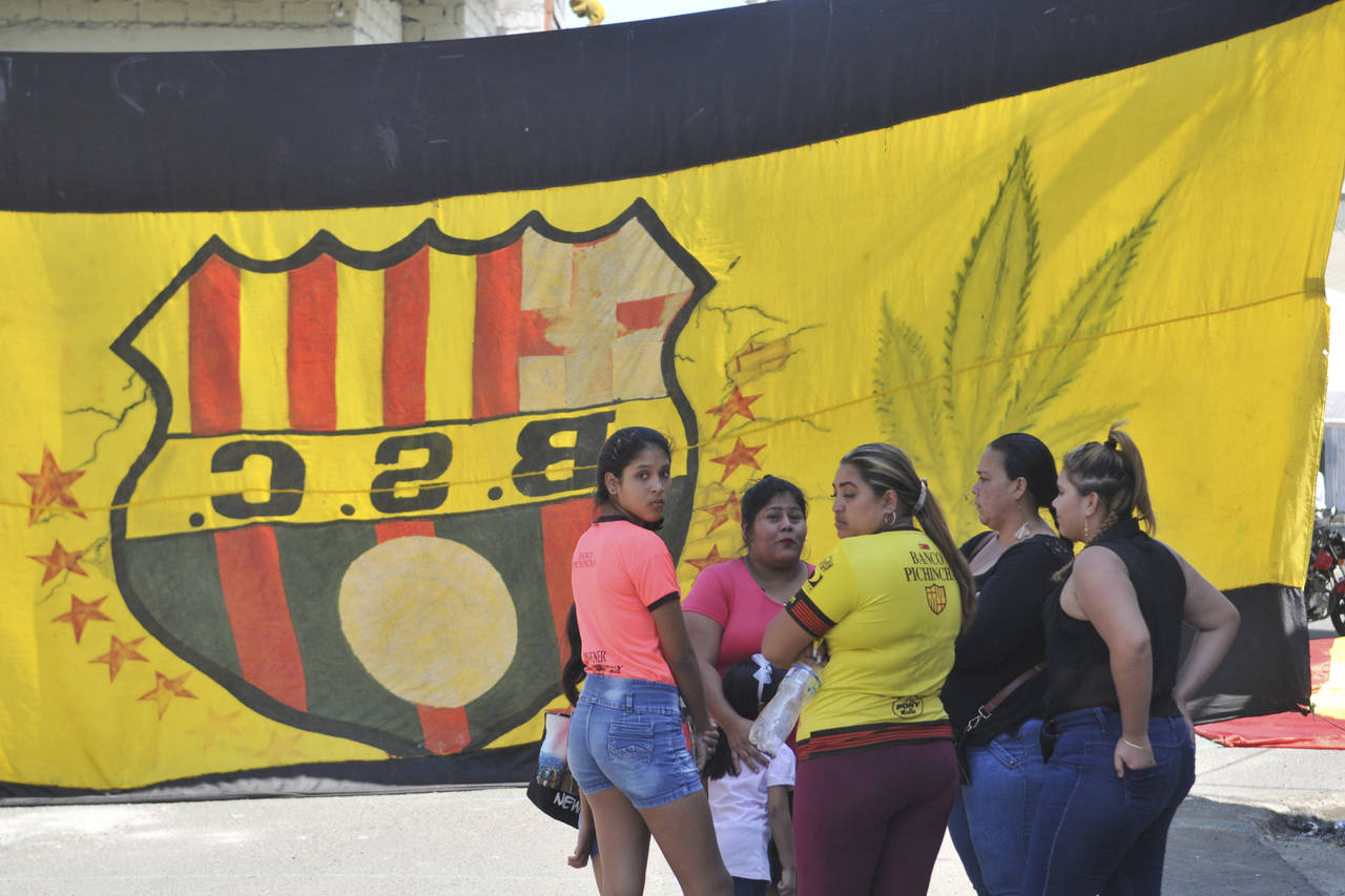 Un grupo de mujeres conversa frente a la casa de un hincha del Barcelona de Ecuador, fallecido junto con otros 11 en un accidente de autobús, ayer. (AP)