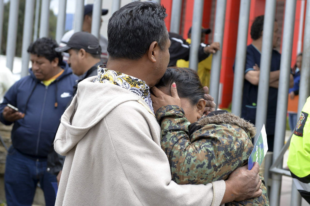 La gente se abraza mientras espera noticias afuera de la morgue sobre sus familiares, quienes eran hinchas de un equipo de futbol. (AP)