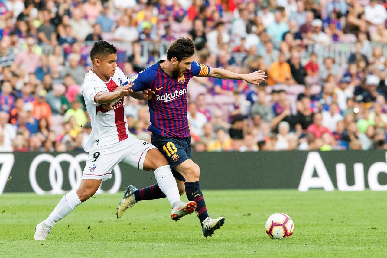 El delantero argentino del Barcelona Leo Messi (d) lucha con Juan Hernández, del Huesca, durante el partido de la tercera jornada de Liga en Primera División en el Camp Nou.