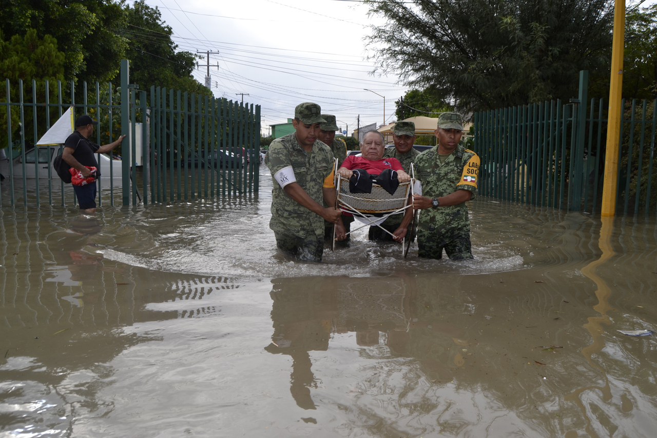 Apoyo. Soldados cargan a don Lorenzo, un hombre sin pies, para sacarlo de la inundación. (EDITH GONZÁLEZ) 