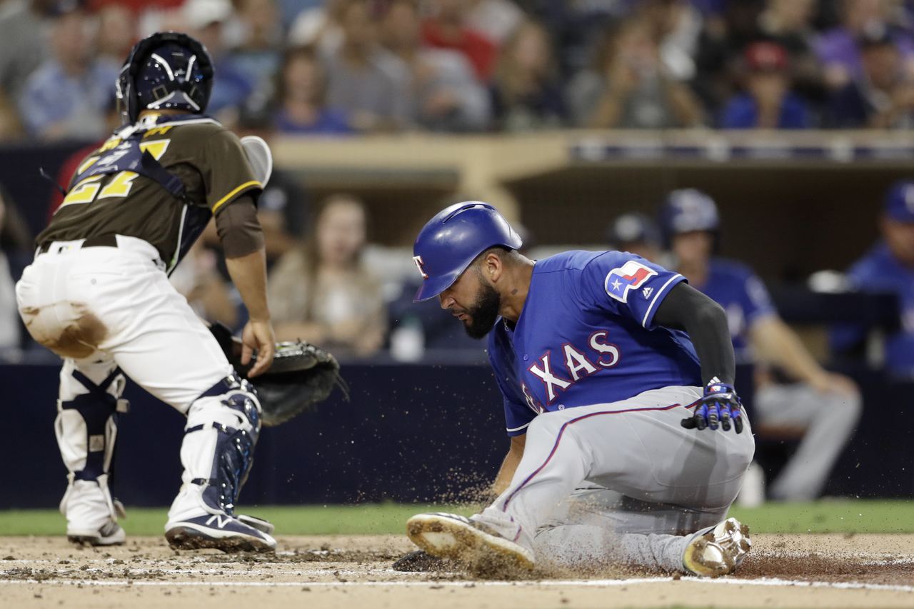 El jugador de los Rangers de Texas Nomar Mazara (derecha) anota desde segunda base en un sencillo de Jurickson Profar ante el catcher de los Padres de San Diego Francisco Mejía, en el segundo inning del juego.