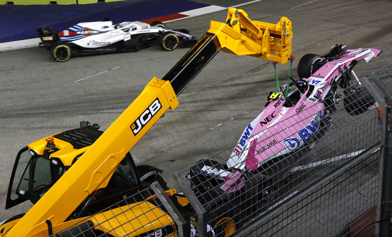 Una grúa se lleva el monoplaza del francés Esteban Ocon luego del accidente que tuvo con su coequipero Sergio 'Checo' Pérez en la primera vuelta del Gran Premio de Singapur.