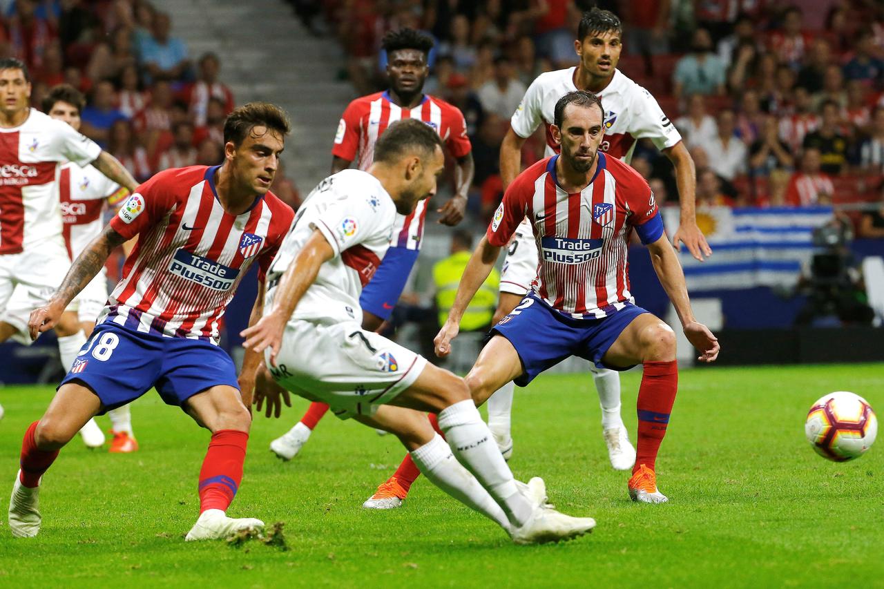 El centrocampista del Huesca, David Ferreiro (c), golpea el balón ante los jugadores del Atlético de Madrid, Carlos Isaac (i) y el uruguayo Diego Godín, durante el encuentro correspondiente a la sexta jornada.