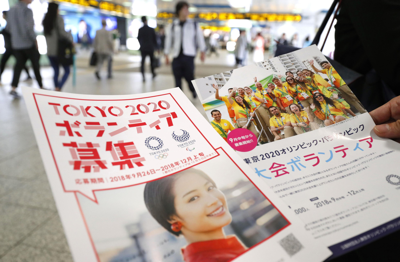 Panfletos para reclutar voluntarios para los Juegos Olímpicos y Paralímpicos de 2020 son repartidos en una estación de trenes en Tokio.
