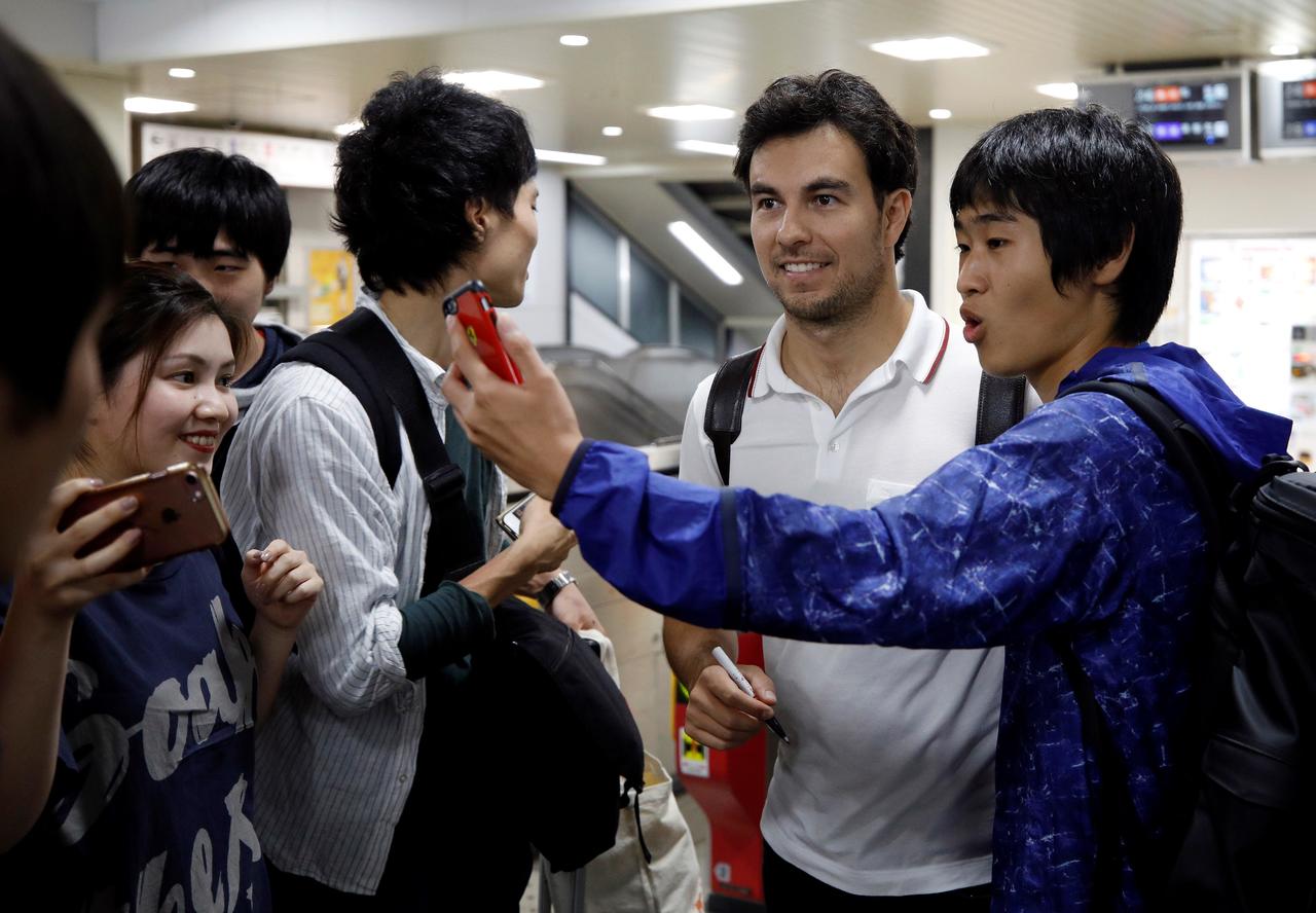 El mexicano Sergio Pérez (c), de la escudería Sahara Force India, posa con varios seguidores a su llegada a la estación Shiroko en Suzuka, Japón.