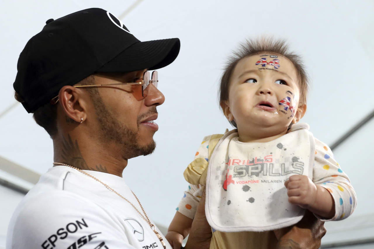 El piloto Lewis Hamilton (Mercedes) carga a un bebé durante un encuentro con aficionados de la Fórmula Uno en la antesala del Gran Premio de Japón en Suzuka.