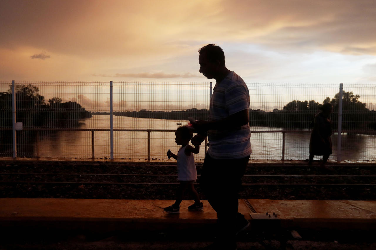 Paso. Migrantes hondureños esperan junto con su hijo en el puente de la frontera entre Guatemala y México. (EFE)